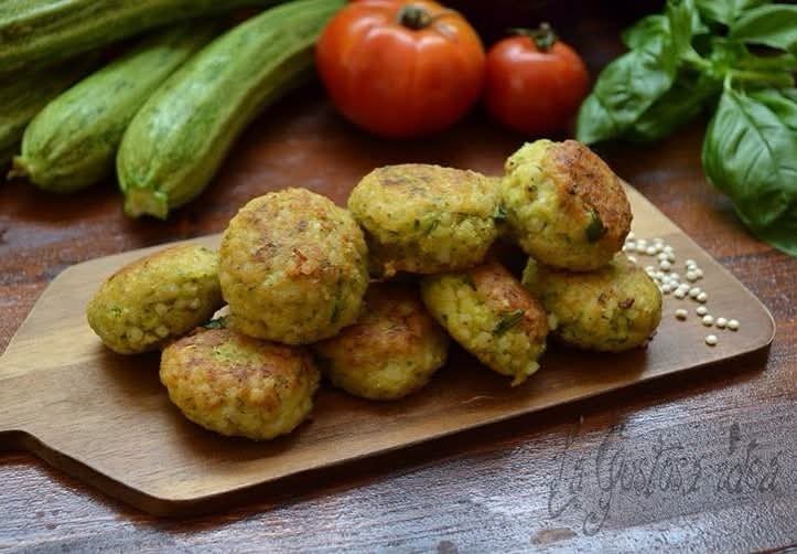 Polpette di sorgo e zucchine cotte al forno, dorate e croccanti, servite su tagliere di legno.