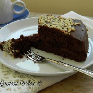 Fetta di torta al cacao con crema al cioccolato, ganache fondente e granella di nocciole